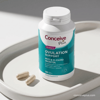 Supplement bottle labeled 'Conceive Plus' on a white surface with two capsules beside it.
